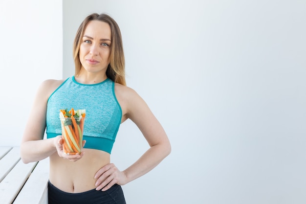 Concepto de dieta - mujer de estilo de vida saludable con verduras en el interior. Hembra joven comiendo alimentos saludables