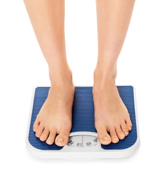 Concepto de dieta Pies descalzos femeninos de pie en la balanza
