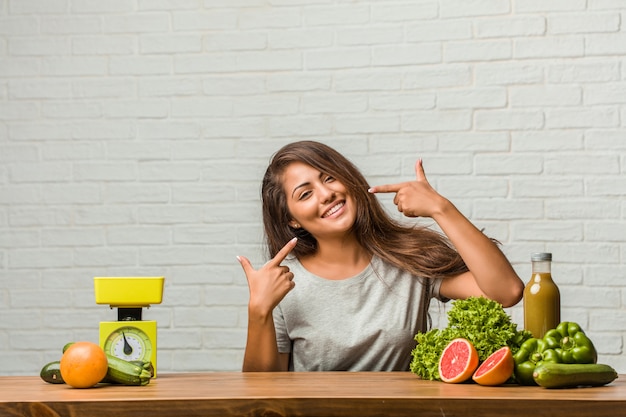 Concepto de dieta. El retrato de una mujer latina joven y saludable sonríe, señala con la boca, el concepto de dientes perfectos, dientes blancos, tiene una actitud alegre y jovial