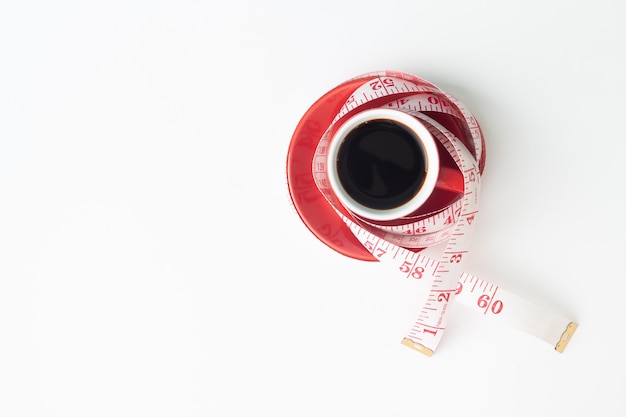 concepto de dieta y saludable con café negro en taza roja y cinta métrica