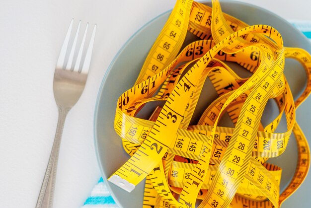 El concepto de la dieta. El tenedor rebobinado centímetro acostado en primer plano de la placa