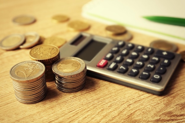 Concepto de dinero Calculadora gris con monedas y cuaderno en mesa de madera