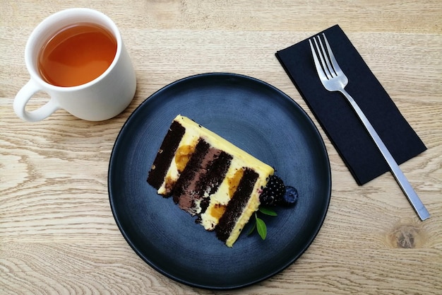 Concepto de diseño de alimentos creativos vista superior plato azul oscuro taza de té tenedor pastel