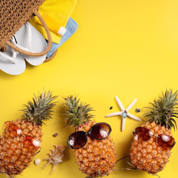 Concepto de diseño de fondo de frutas de verano. Vista superior de la playa de viajes de vacaciones con conchas, piña y hojas de palmera sobre fondo amarillo.