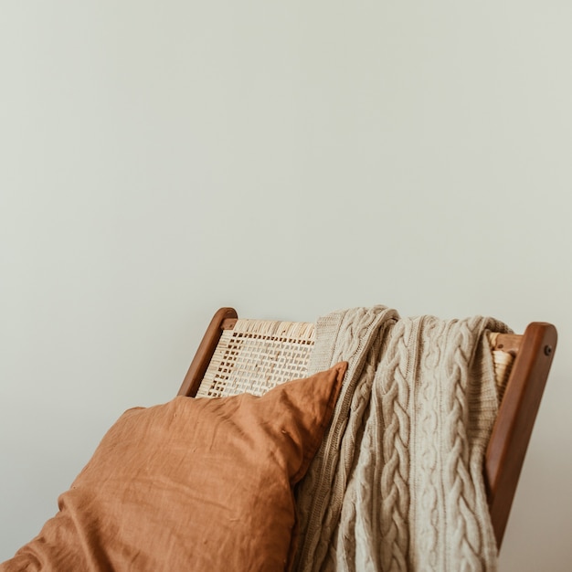 Concepto de diseño de interiores moderno. Silla de madera de ratán con estilo, tela escocesa de punto, almohada de jengibre