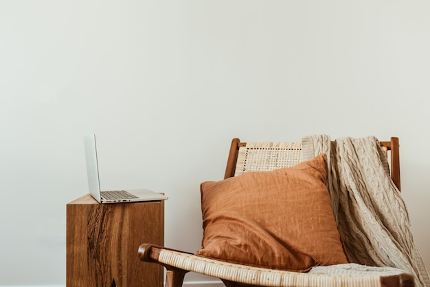 Concepto de diseño de interiores moderno. Silla de madera de ratán con estilo, tela escocesa de punto, almohada de jengibre