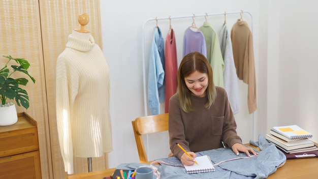 Concepto de diseño de moda Diseñador de moda midiendo el tamaño de la camisa y tomando notas en el cuaderno