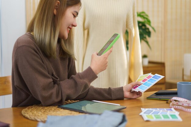 Concepto de diseño de moda Diseñador de moda tomando una foto de la muestra de color en el teléfono inteligente mientras dibuja