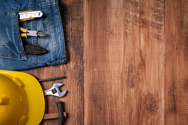 Concepto de diseño de vista superior del Día del Trabajo con herramientas de trabajo y jeans sobre fondo de mesa de madera.