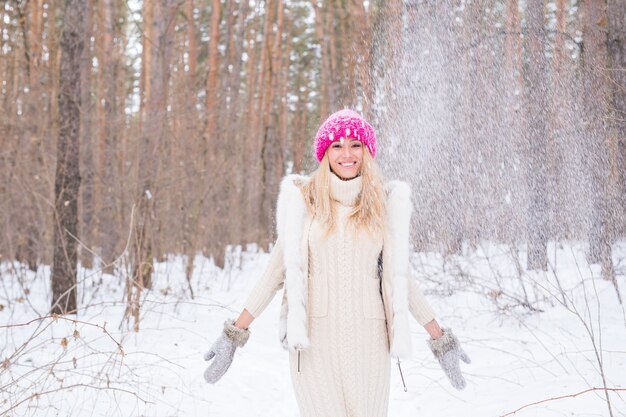 Concepto de diversión, invierno y personas - mujer atractiva vestida con bata blanca arrojando nieve.