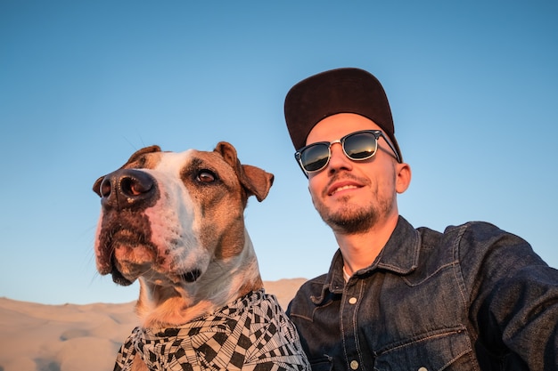 Concepto divertido de mejores amigos: humanos tomando un selfie con perro. Varón joven hace un autorretrato mimado con su perro al aire libre