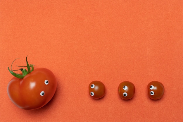 Concepto divertido de los tomates con los ojos, espacio de la copia