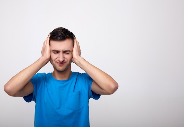 Concepto de dolor de cabeza Malestar infeliz joven apretando la cabeza con las manos