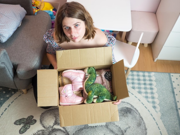 Concepto de donación de ropa de bebé de invierno. Mujer preparando ropa vieja usada en casa.