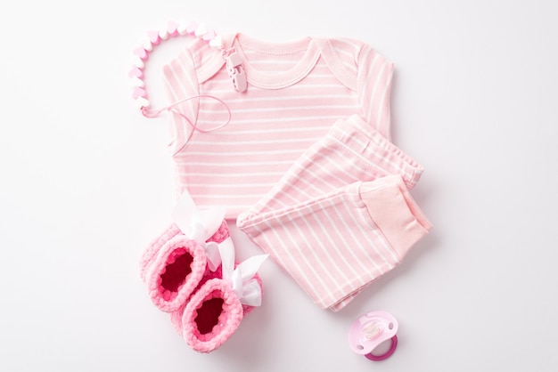 Foto concepto de ducha de bebé foto de la vista superior de ropa rosa para bebés camisa pantalones cadena de dientes de maniquí y botas de punto sobre un fondo blanco aislado