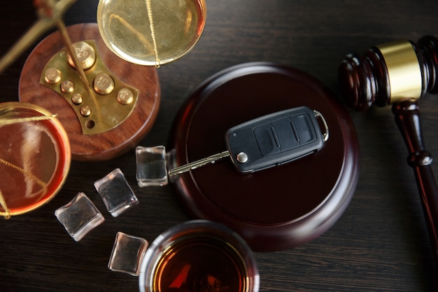 Foto el concepto de dui. martillo de ley, alcohol y llaves del coche en la mesa de madera, fondo oscuro