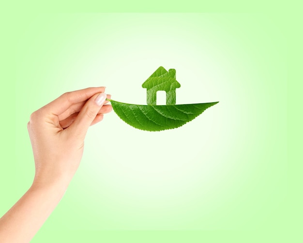 Foto el concepto de ecología de la hoja verde en la mano con el invernadero