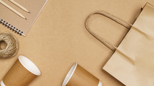 Concepto ecológico Bolsa de papel vaso de papel cuerda de yute y cuaderno con lápiz sobre fondo de madera