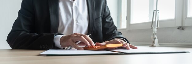 Concepto de economía y finanzas - asesor financiero sentado en su escritorio haciendo cálculos en la calculadora naranja.