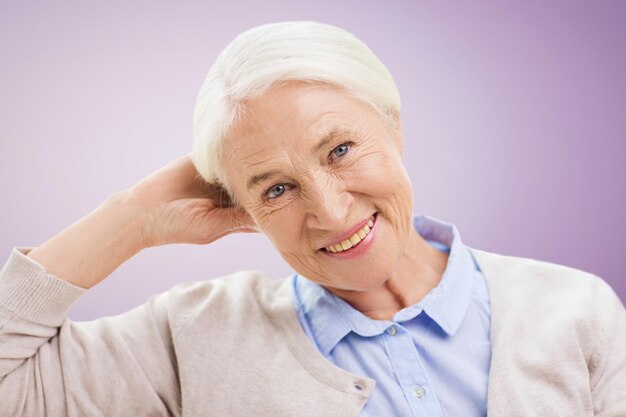 concepto de edad y personas - mujer mayor sonriente feliz sobre fondo violeta