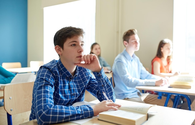 concepto de educación, aprendizaje y personas - estudiante feliz con libro en la lección de la escuela