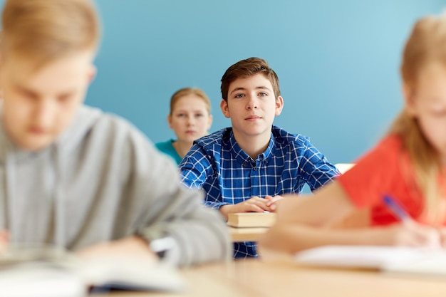 concepto de educación, aprendizaje y personas - grupo de estudiantes con cuadernos en la lección escolar