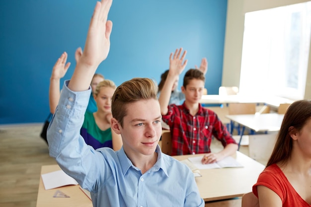 Foto concepto de educación, aprendizaje y personas - grupo de estudiantes levantando la mano en la lección escolar