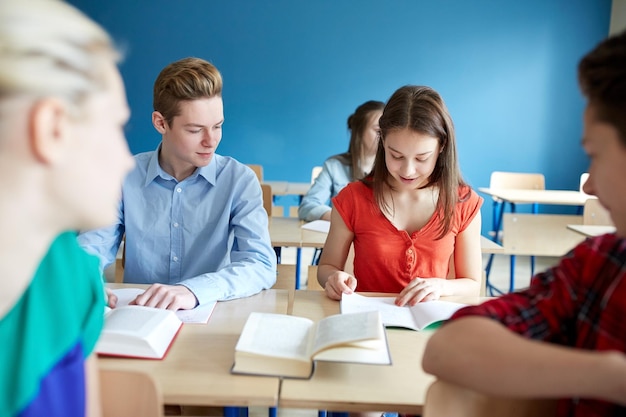 concepto de educación, aprendizaje y personas - grupo de estudiantes con libros en la lección escolar