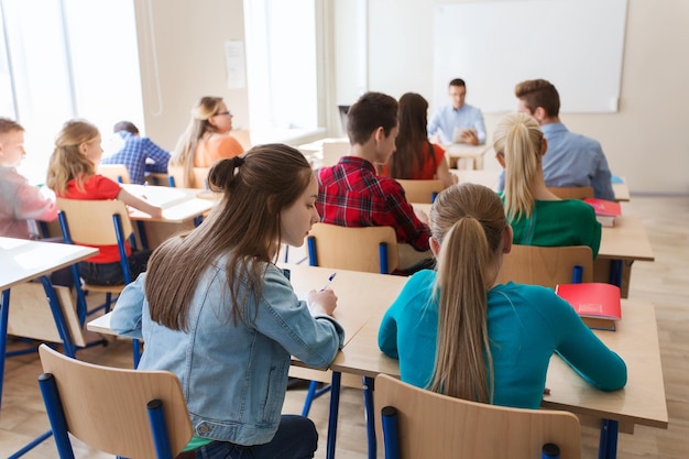 concepto de educación, aprendizaje y personas - grupo de estudiantes que escriben pruebas escolares