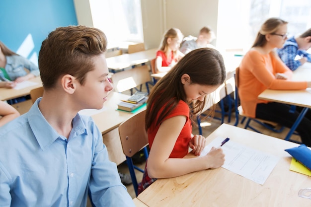 Foto concepto de educación, aprendizaje, trampa y personas - grupo de estudiantes que escriben pruebas escolares