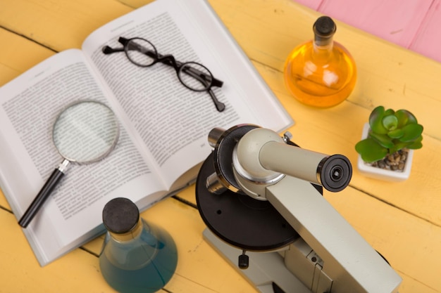 Concepto de educación y ciencia microscopio libro lupa anteojos y líquidos químicos