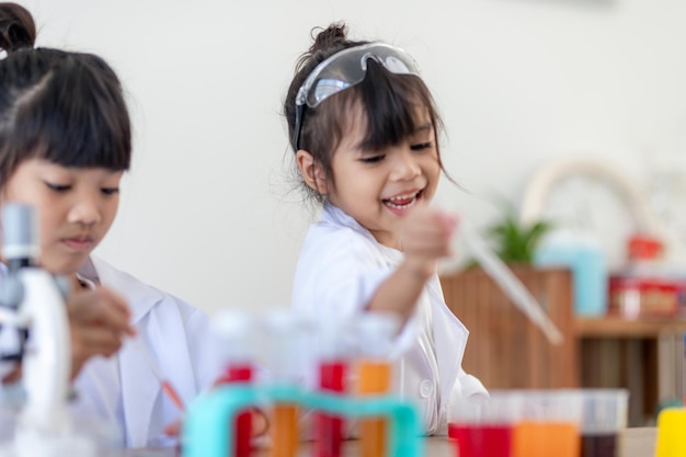 Concepto de educación, ciencia, química y niños: niños o estudiantes con tubos de ensayo haciendo experimentos en el laboratorio escolar