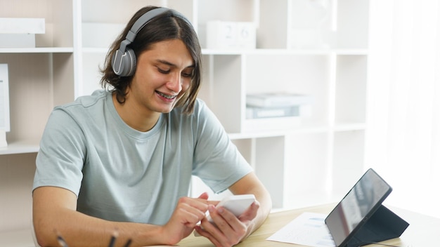 Foto concepto de educación a distancia adolescente con auriculares para escuchar música y usar el teléfono después de estudiar en línea