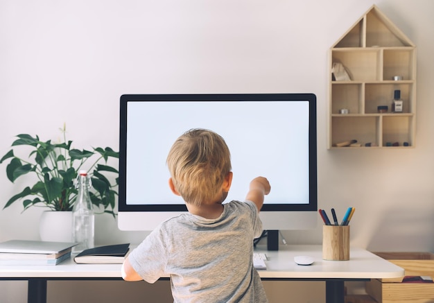 Concepto de educación a distancia Niños aprendiendo en línea Niño que usa tecnología informática en la educación en el hogar Niño que estudia en Internet con una computadora con pantalla en blanco en el hogar Educación en el hogar de los niños