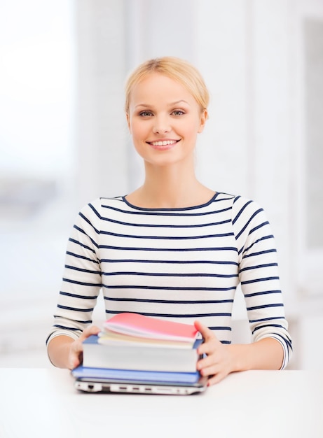 concepto de educación e internet - estudiante sonriente con laptop, libros y cuadernos en la universidad