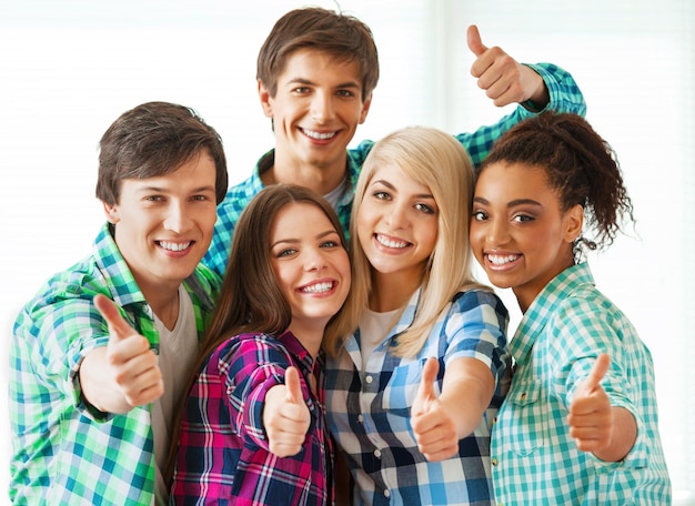 Foto concepto de educación equipo feliz de estudiantes mostrando pulgares hacia arriba en la escuela