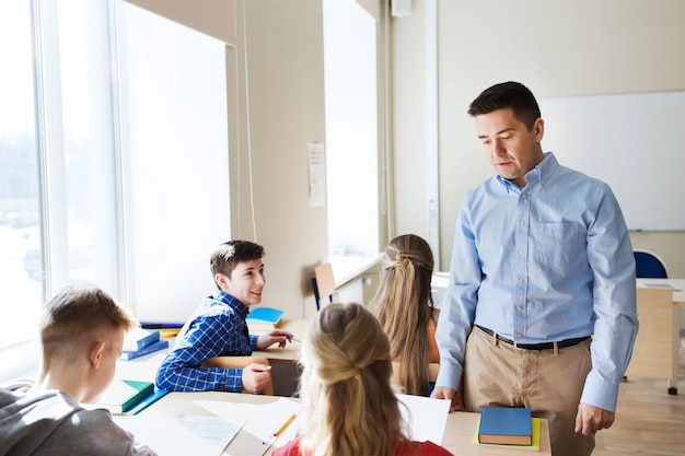 concepto de educación, escuela, aprendizaje, enseñanza y personas - grupo de estudiantes y profesores hablando en el aula