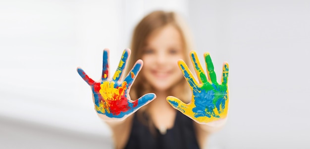 concepto de educación, escuela, arte y pintura - niña estudiante mostrando las manos pintadas