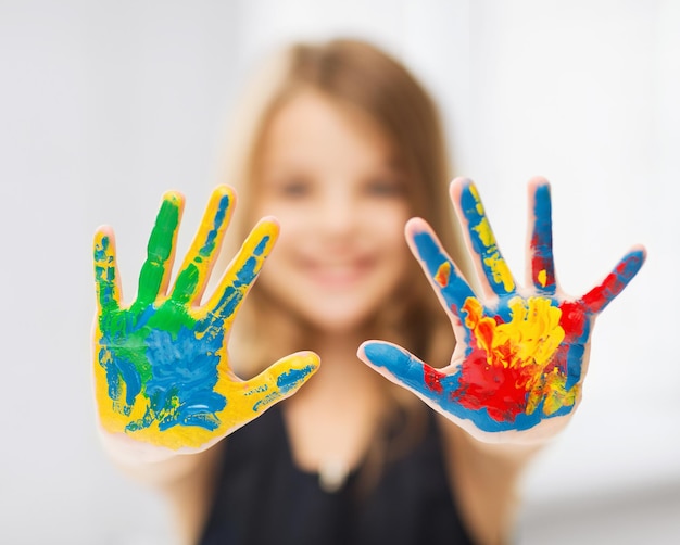 concepto de educación, escuela, arte y pintura - niña estudiante mostrando las manos pintadas