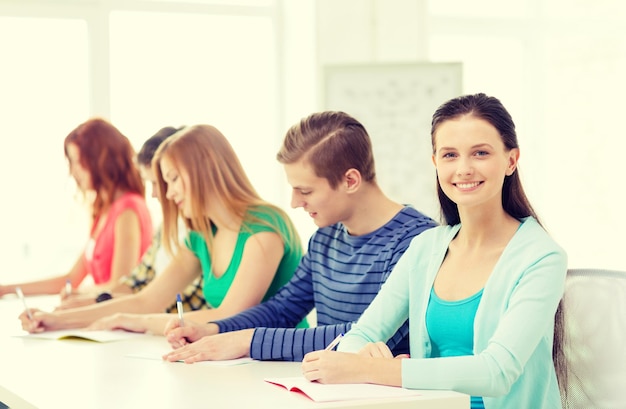 concepto de educación y escuela - cinco estudiantes sonrientes con libros de texto en la escuela