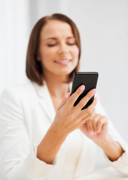 concepto de educación, escuela, negocios, comunicación y tecnología - mujer de negocios sonriente o estudiante con mensajes de texto de teléfonos inteligentes