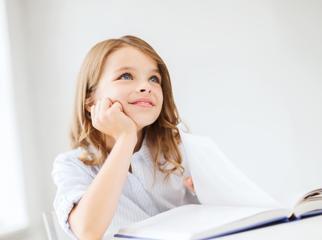 Concepto de educación y escuela - niña estudiante escribiendo en el cuaderno en la escuela