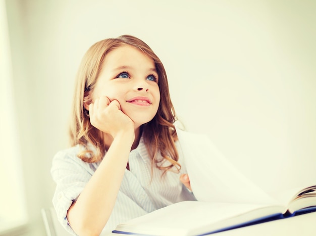 Concepto de educación y escuela - niña estudiante escribiendo en el cuaderno en la escuela