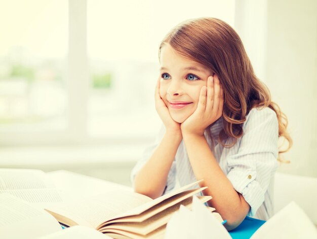 Concepto de educación y escuela - niña estudiante escribiendo en el cuaderno en la escuela