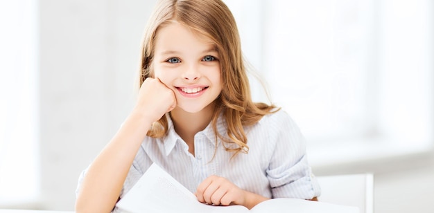 Concepto de educación y escuela - niña estudiante estudiando en la escuela