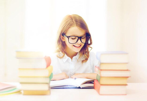 Concepto de educación y escuela - niña estudiante estudiando y leyendo libros en la escuela