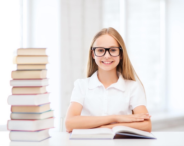 Concepto de educación y escuela - niña estudiante estudiando y leyendo libros en la escuela