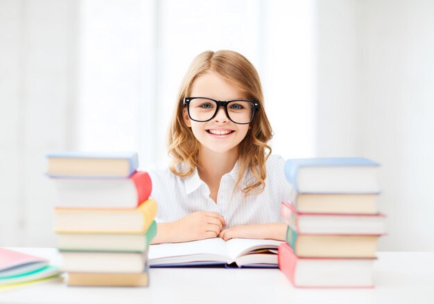 Concepto de educación y escuela - niña estudiante estudiando y leyendo libros en la escuela