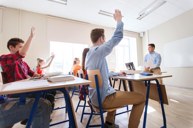 concepto de educación, escuela y personas - grupo de estudiantes felices y profesores con papeles o exámenes