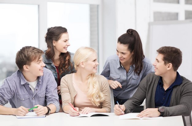 concepto de educación, escuela y personas - grupo de estudiantes sonrientes discutiendo en la escuela